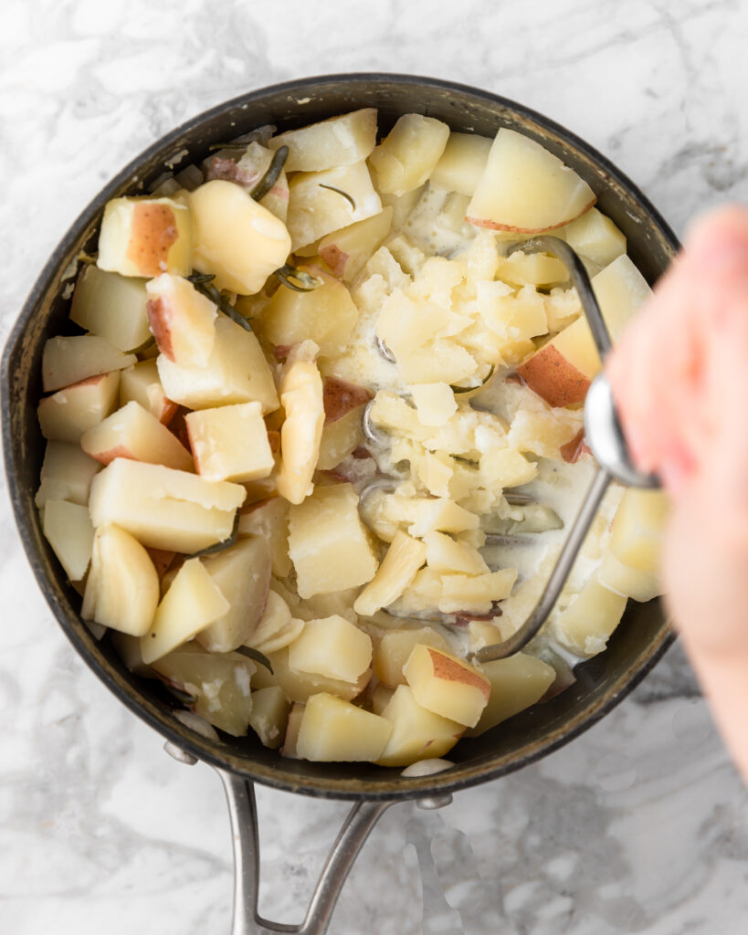 mashing potatoes in a pot.