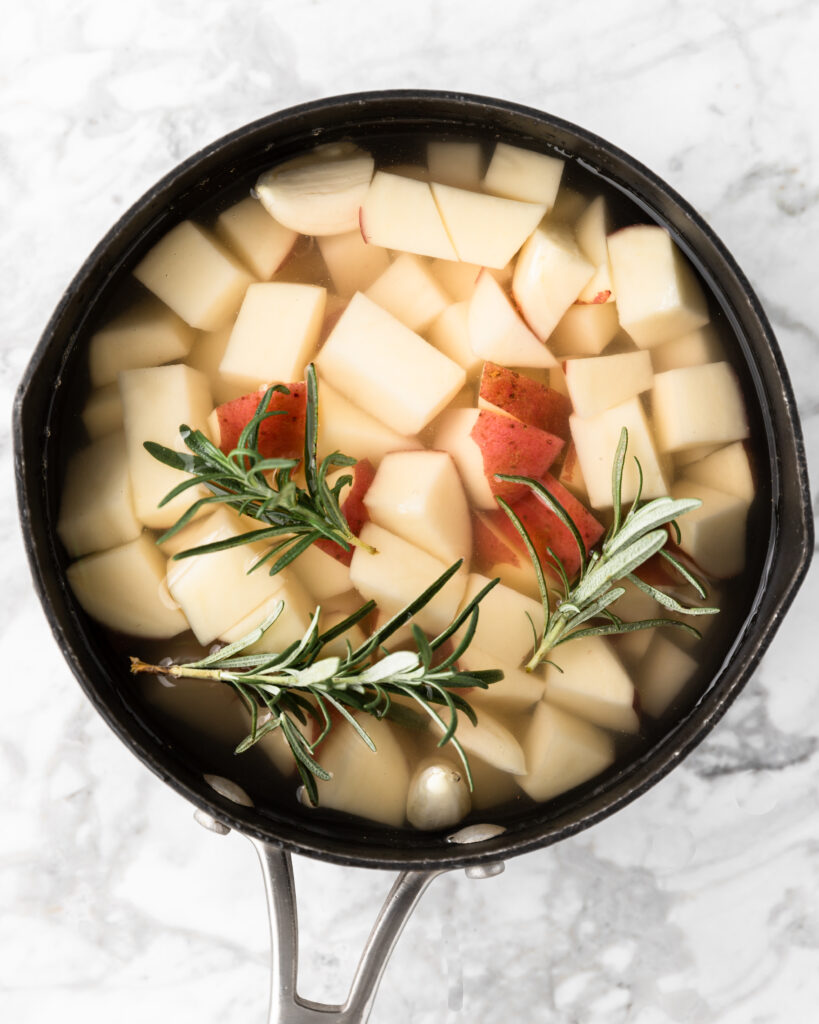 red potatoes with garlic and rosemary in a pot. 