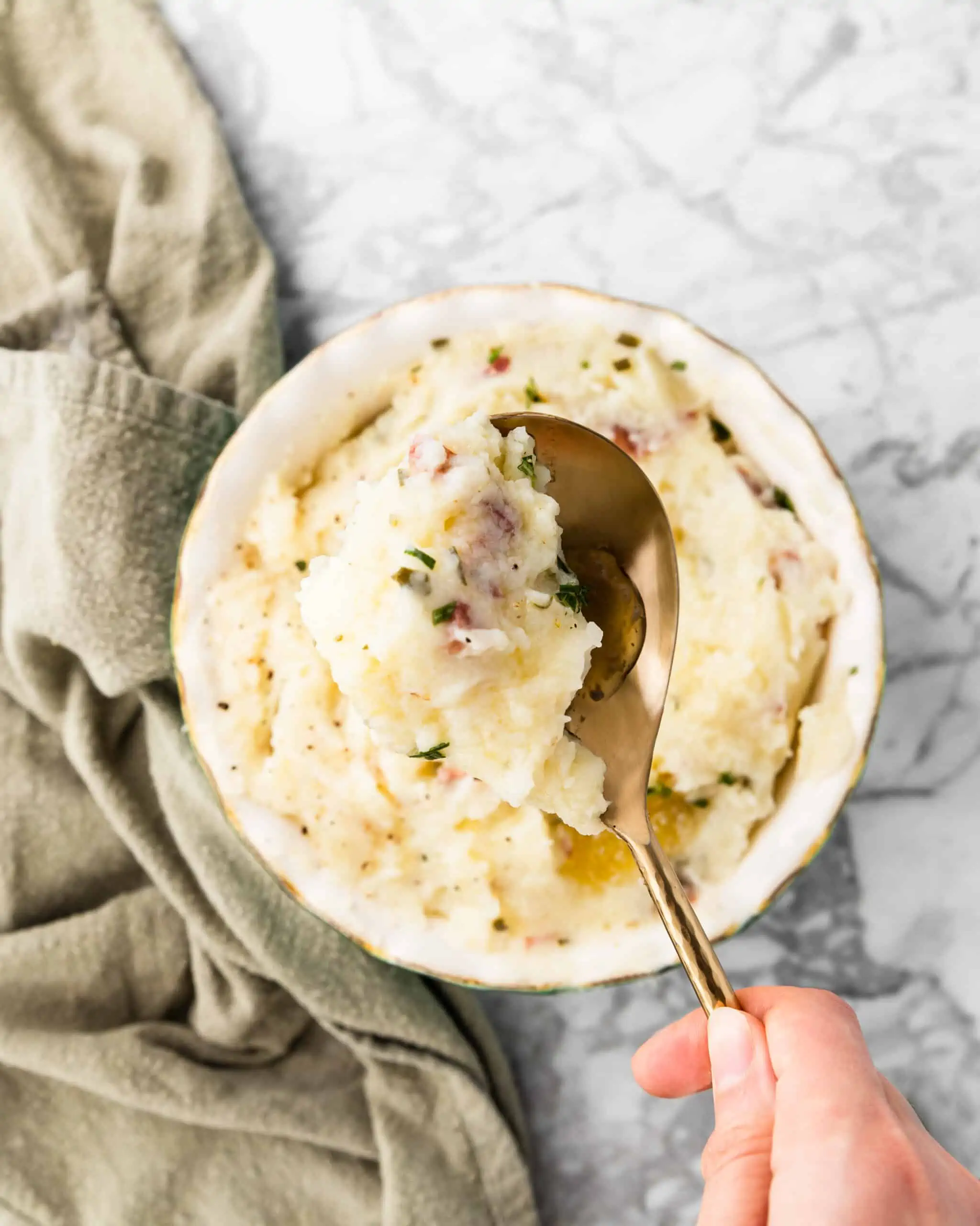 spooning mashed potatoes with rosemary.