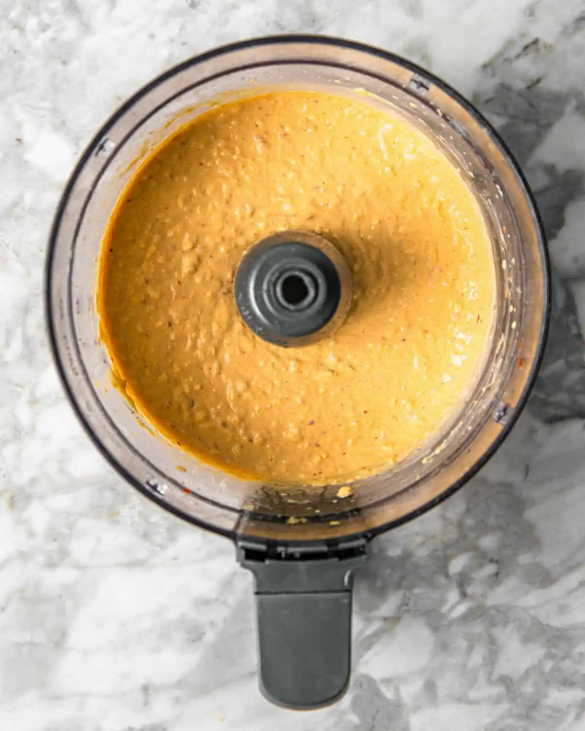blended hummus in a food processor on a counter.