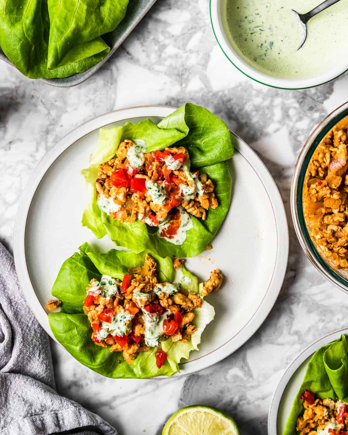 adobo chicken taco lettuce wraps on a plate next to all ingredients on a counter.