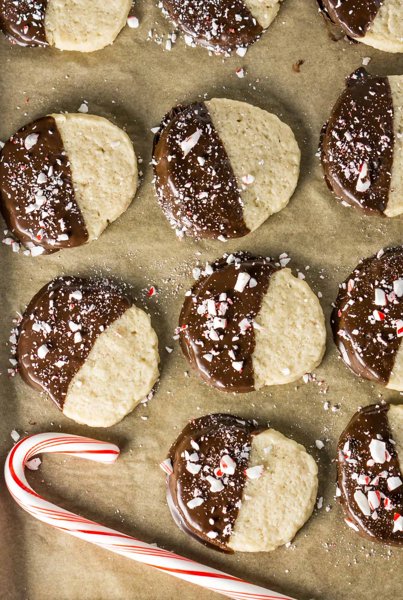 Shortbread Cookies on parchment paper dipped in chocolate with candy cane on top.  