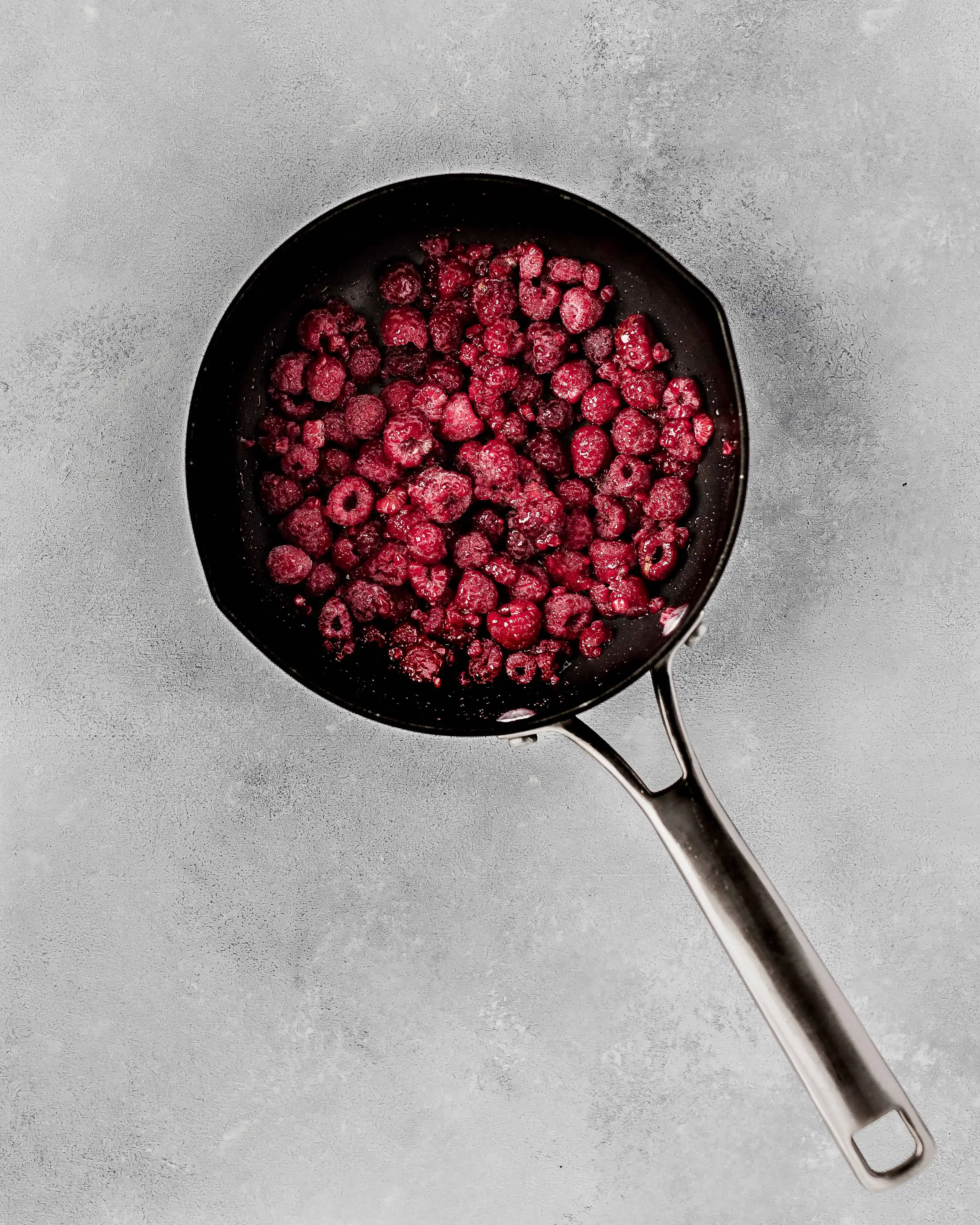 Frozen raspberries in a sauce pan.