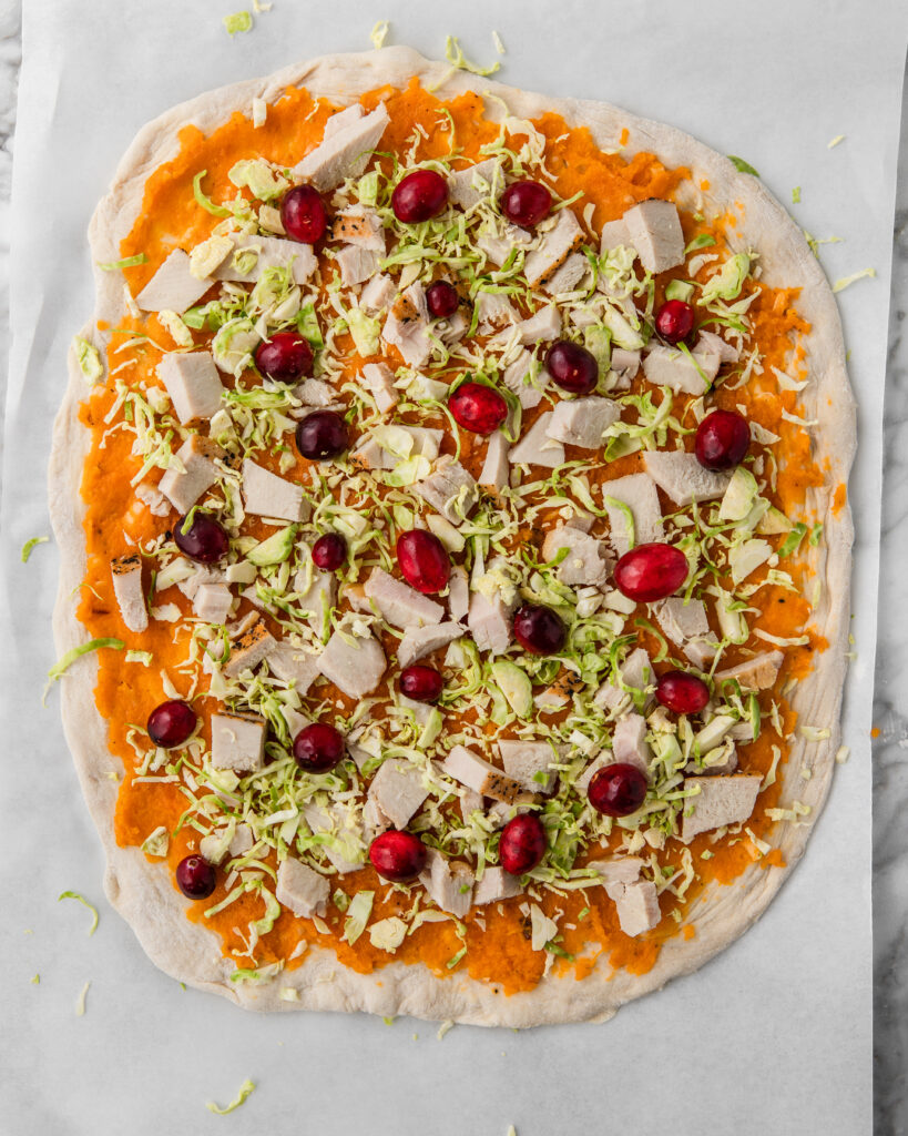 a thanksgiving pizza with cranberries and turkey.
