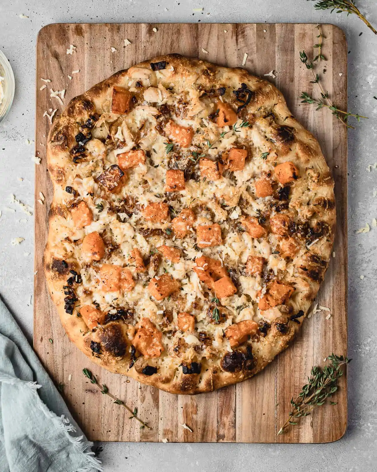 Pizza with butternut squash, chicken and caramelized onions on a cutting board. 