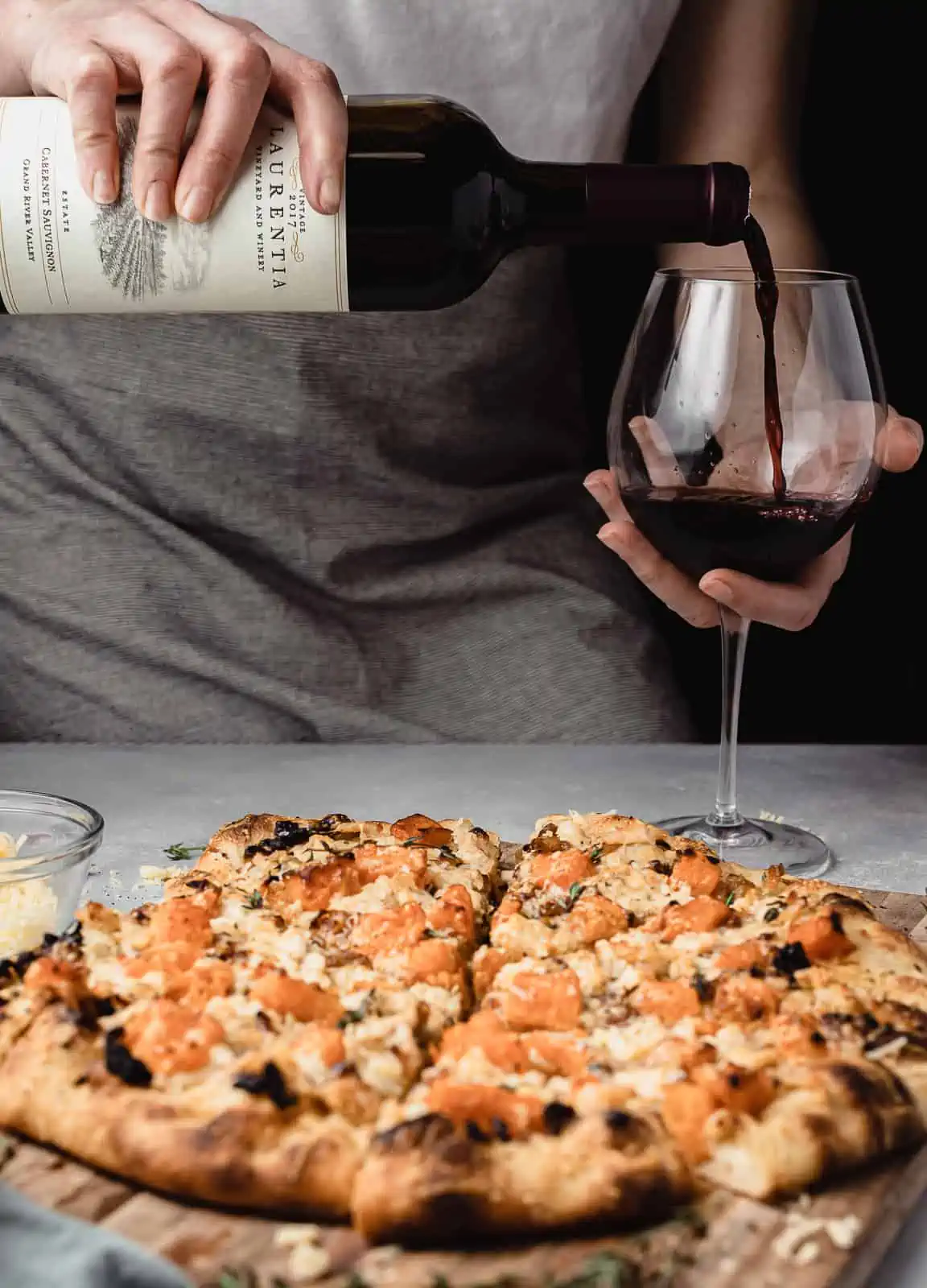 serving butternut squash pizza with a bottle of cabernet sauvignon wine. 