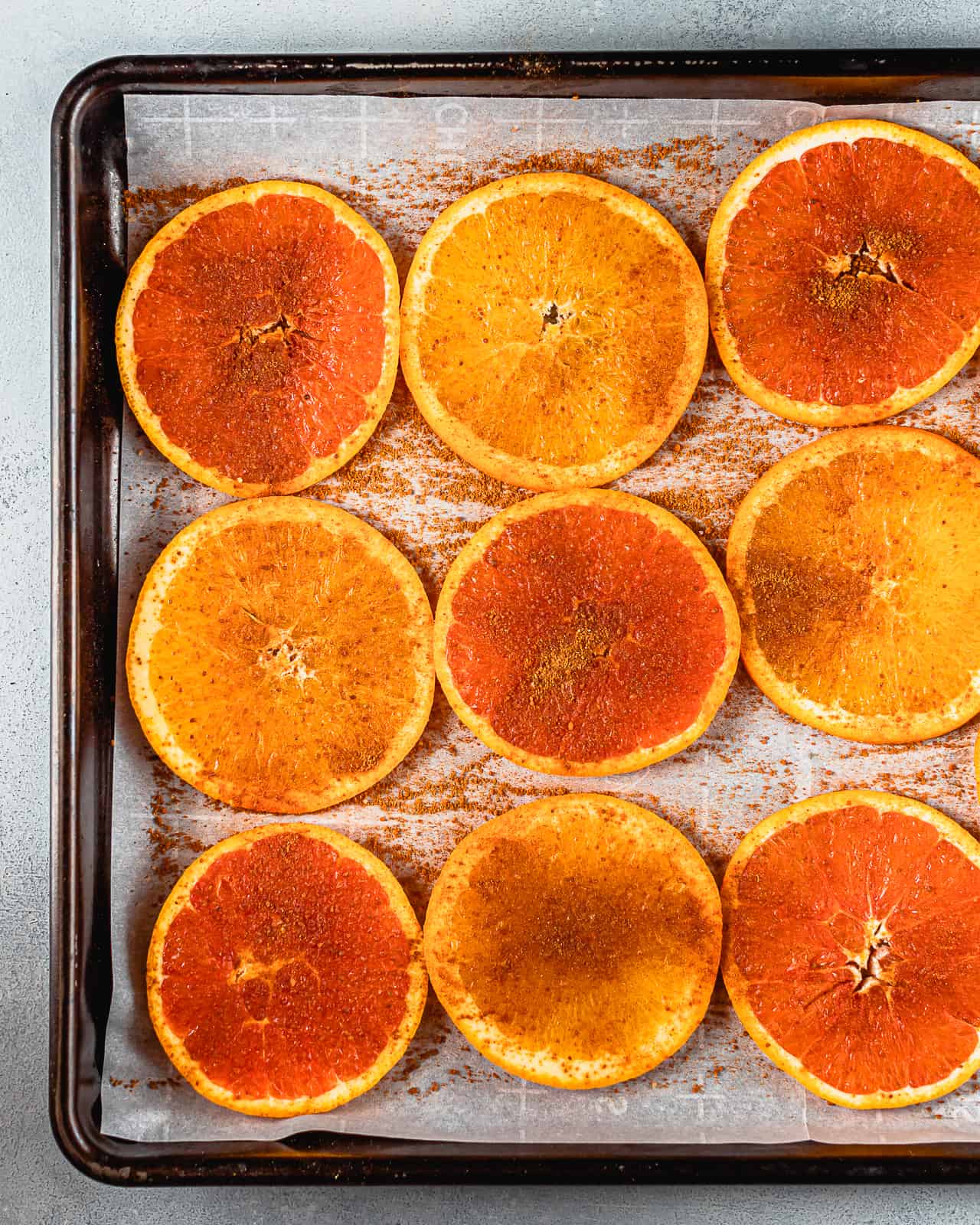 orange slices with spices pre-baking on a baking sheet.