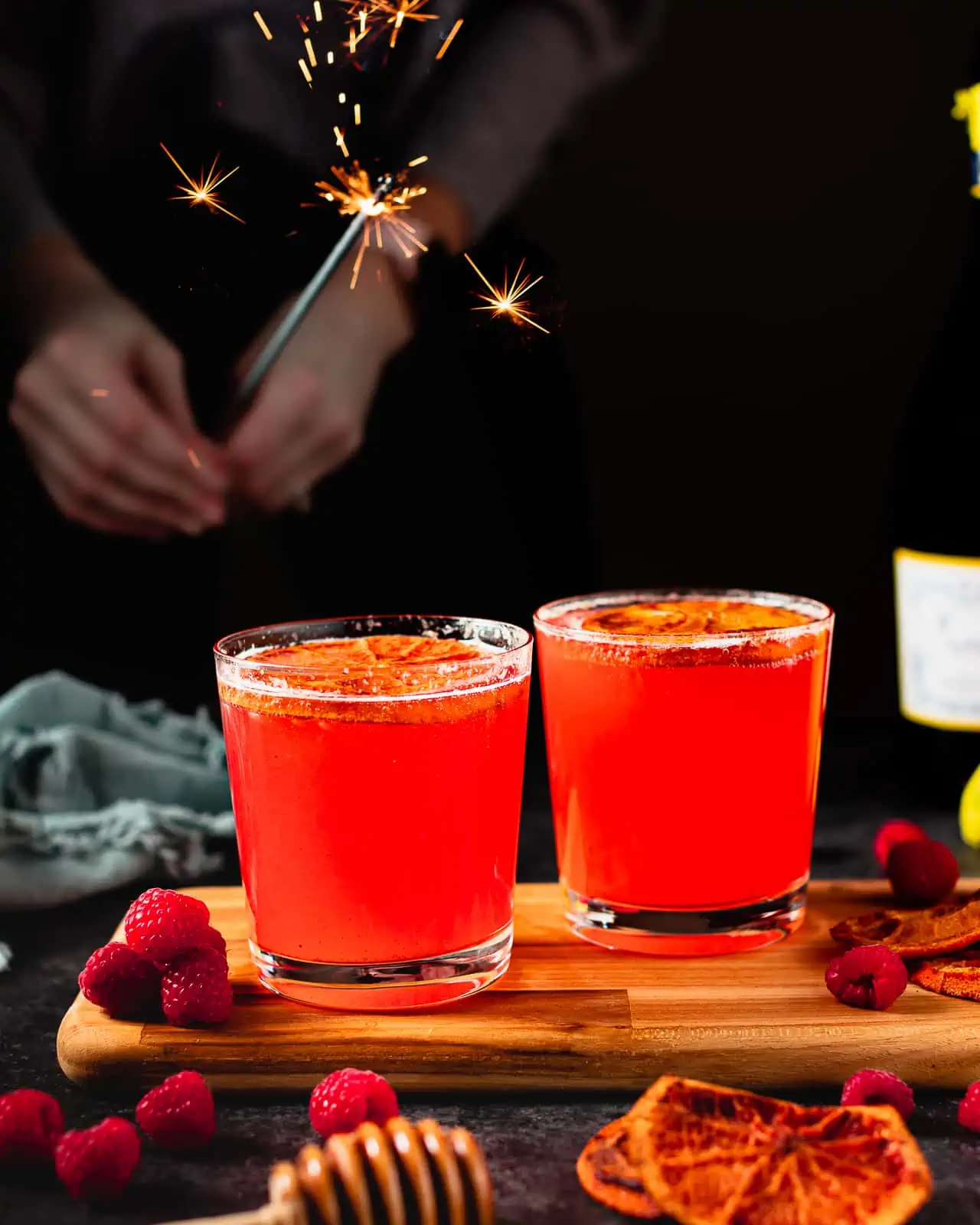 2 glasses of raspberry cocktails with champagne and dried orange slices.