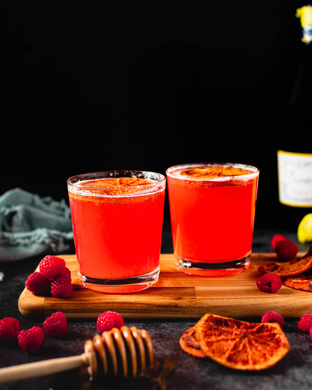2 glasses of raspberry cocktails with champagne and dried orange slices.