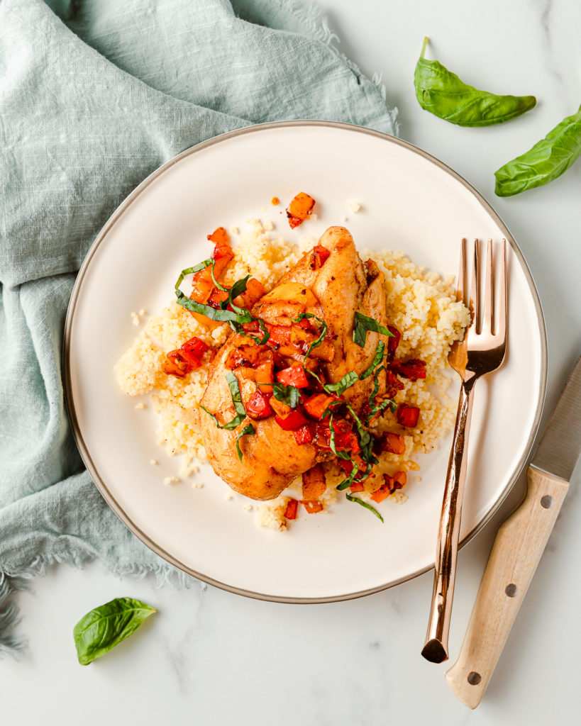 Cooked Balsamic Marinated Chicken Breast served with cooked bell pepper salsa and couscous, topped with fresh basil