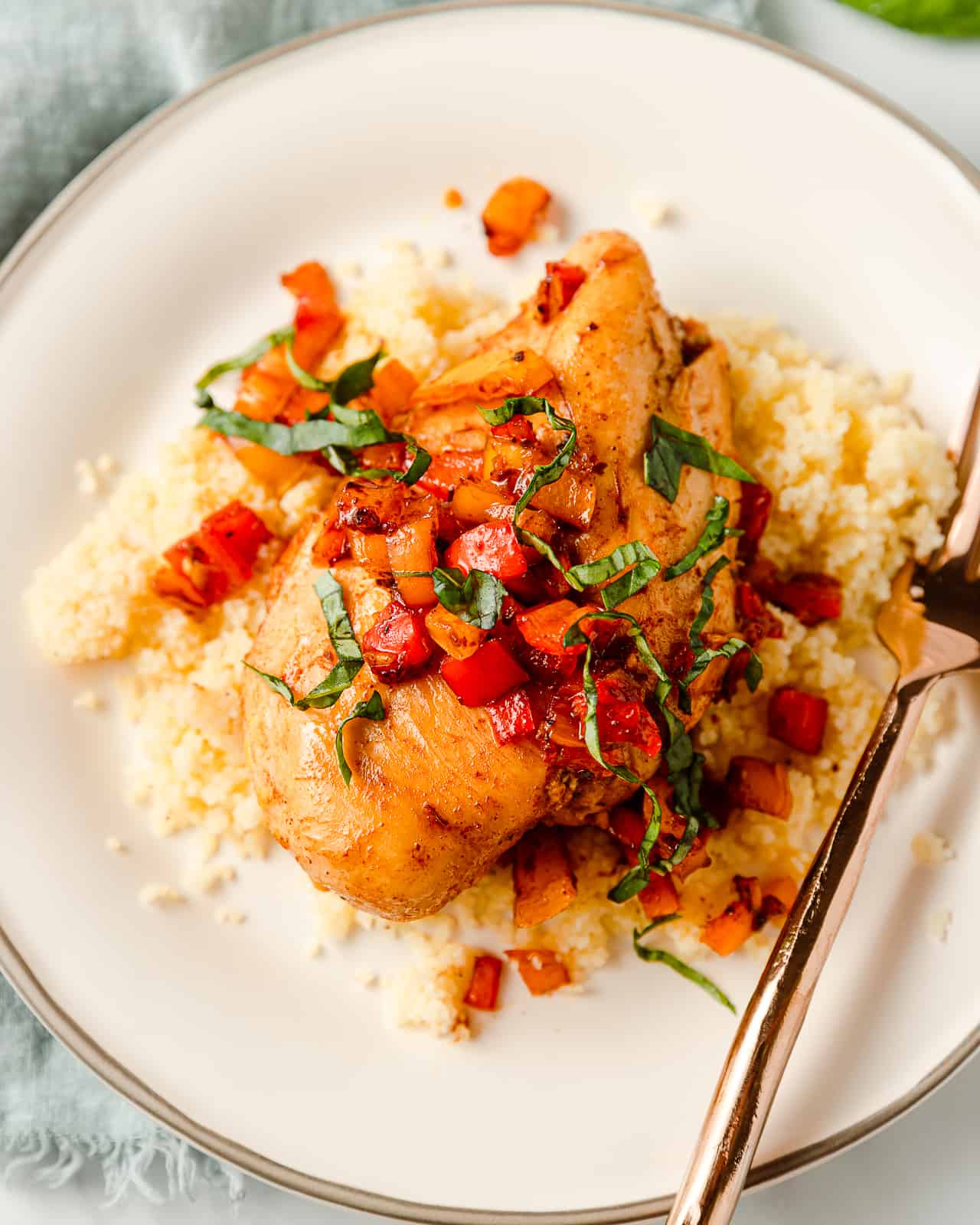 Balsamic Marinated Chicken Breast served with cooked bell pepper salsa and couscous, topped with fresh basil.