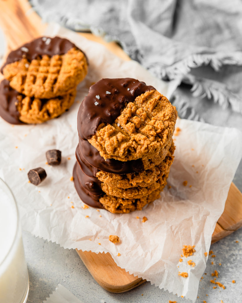 Peanut Butter Cookies dipped in chocolate laying on parchment paper