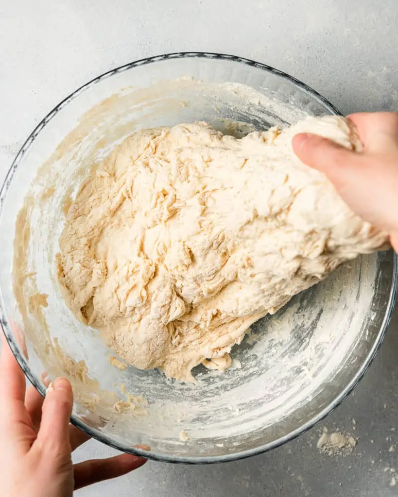 Stretching pizza dough in bowl.