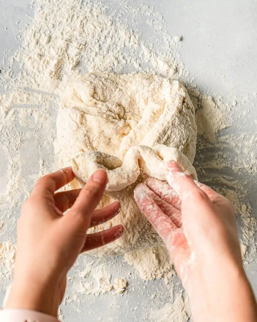 folding pizza dough on a floured surface.