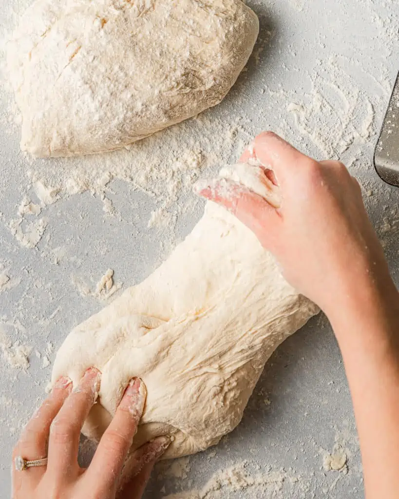 folding pizza dough with hands.