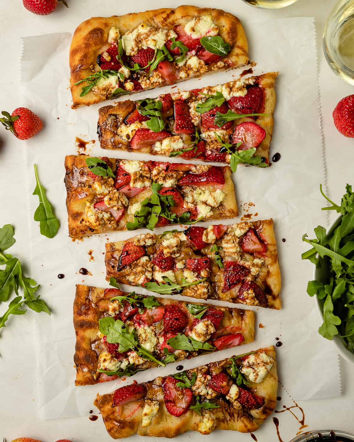 slices of strawberry pizza with goat cheese, arugula, and balsamic glaze. 