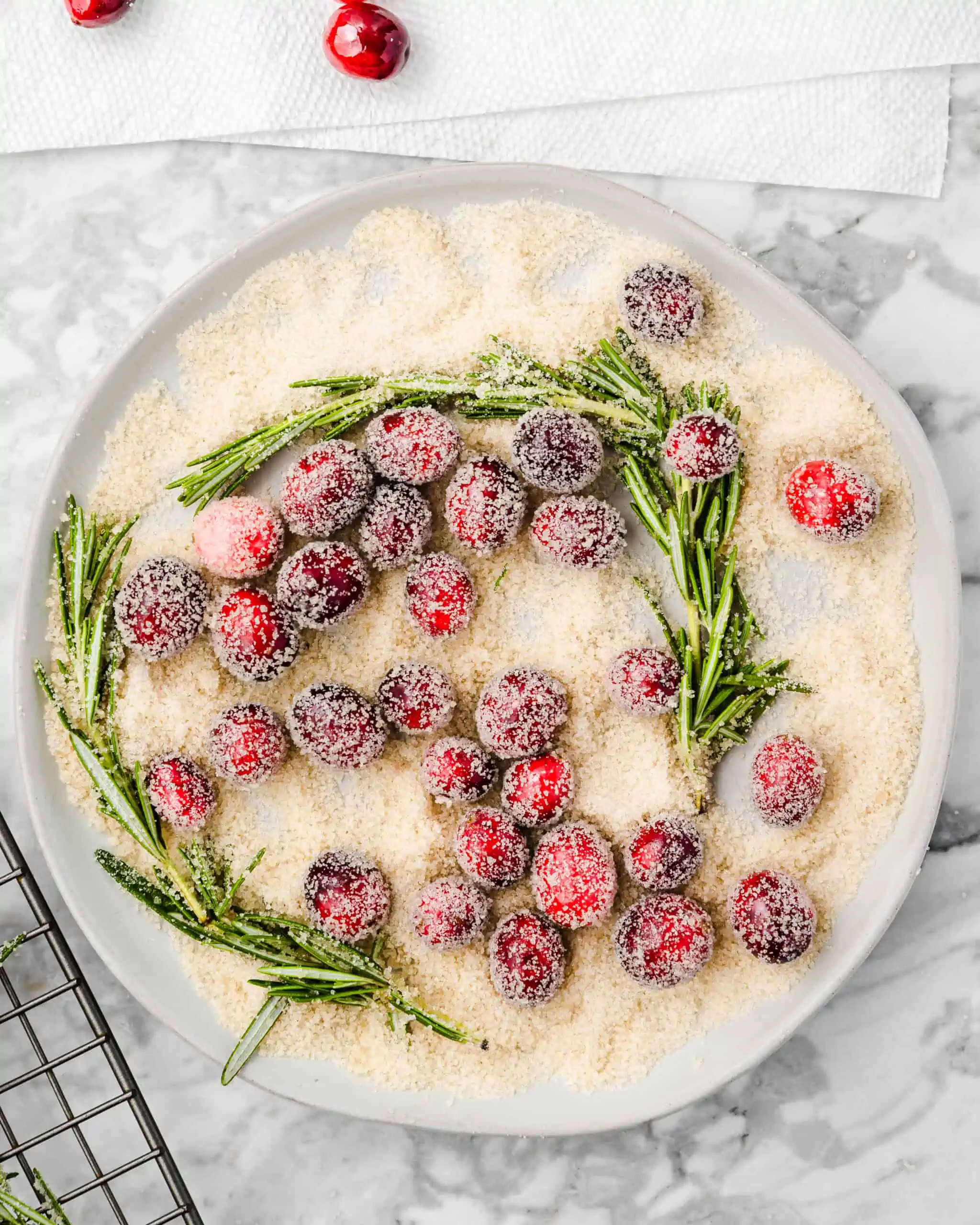 sugared rosemary and cranberries on a plate.