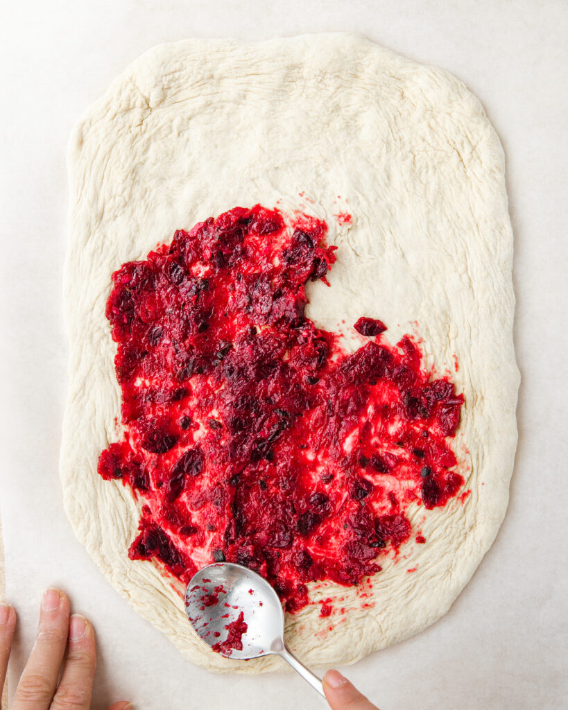 adding cranberry chutney to pizza dough.