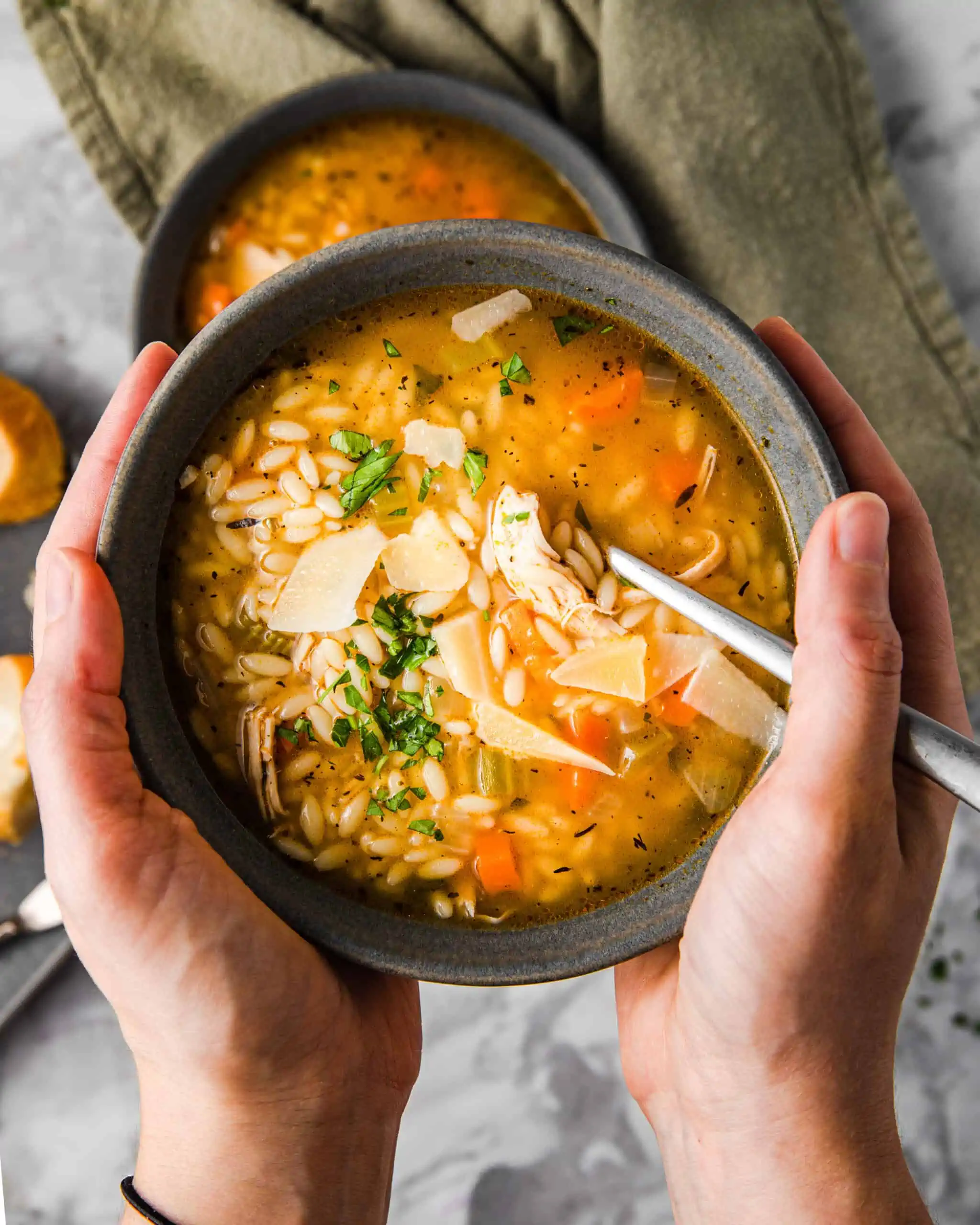 holding a bowl of chicken orzo soup.
