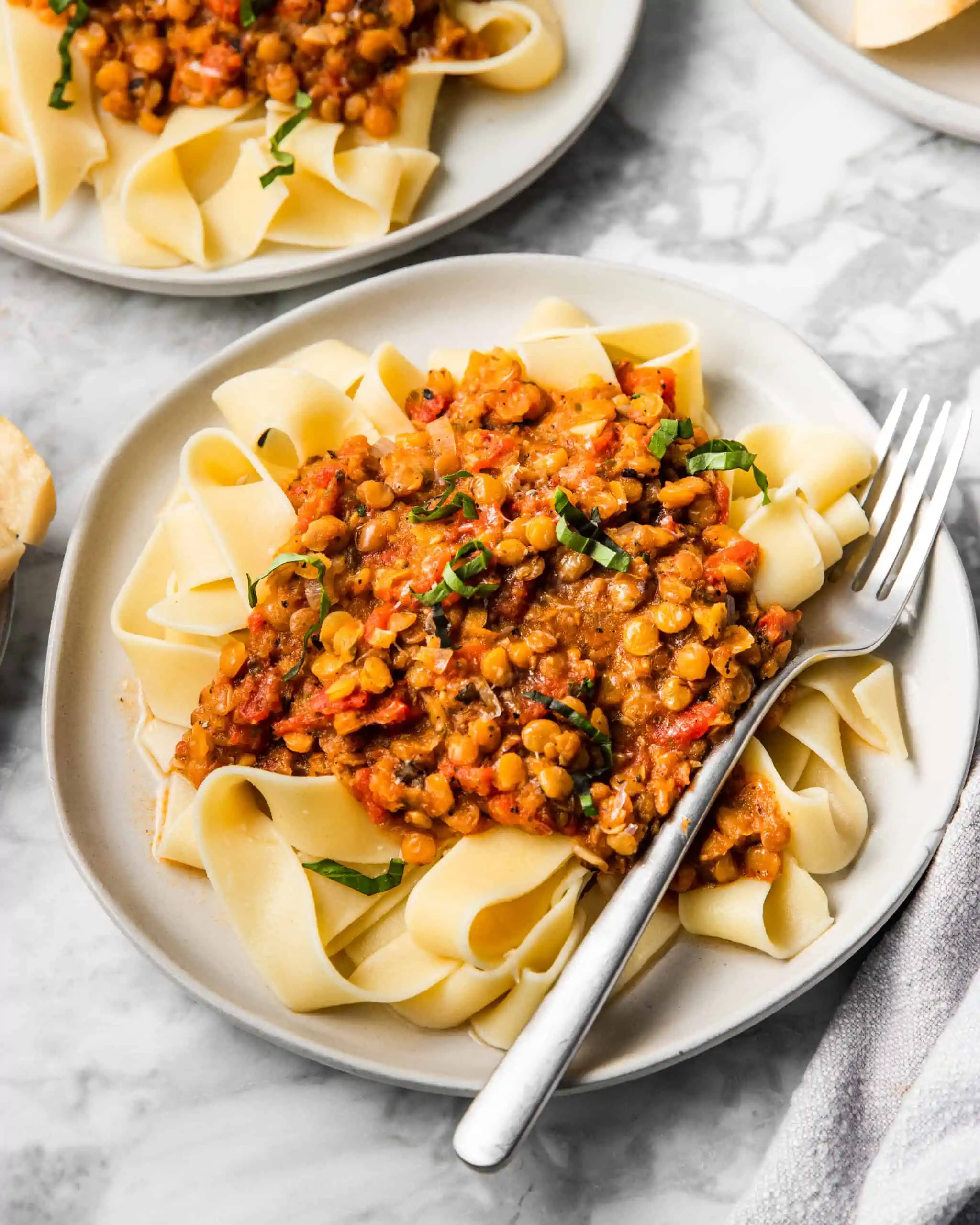 a plate of lentil bolognese topped with fresh basil.