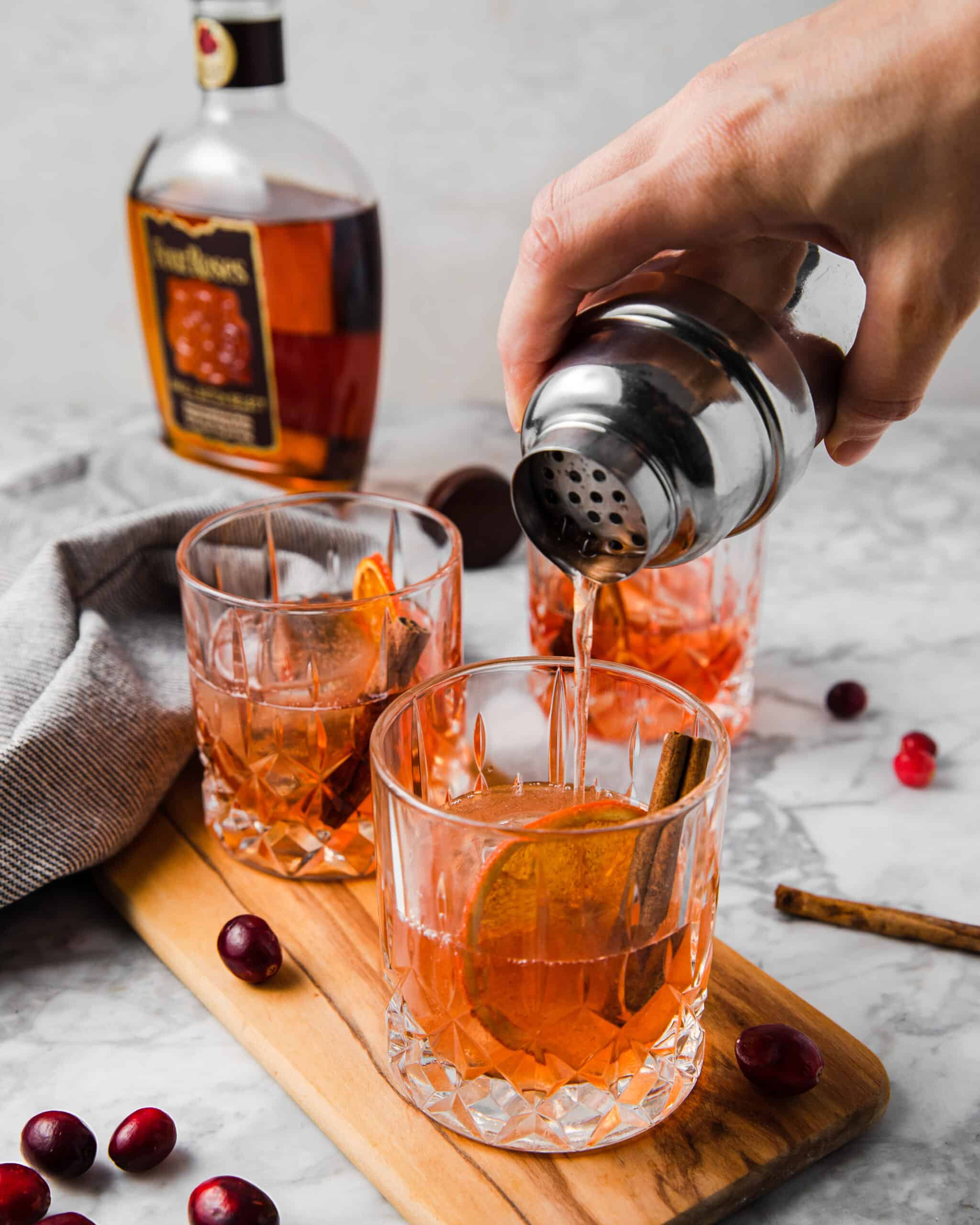 pouring cranberry bourbon drink in a cup.