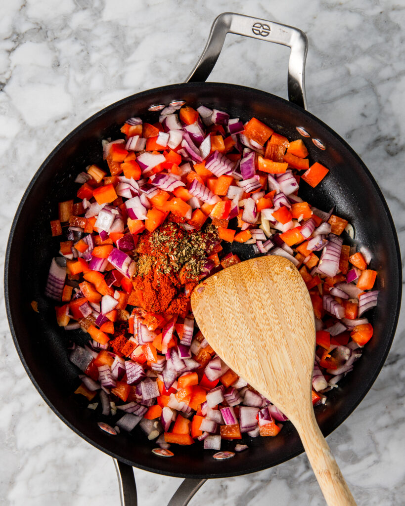 sautéing veggies with seasoning in a pan.