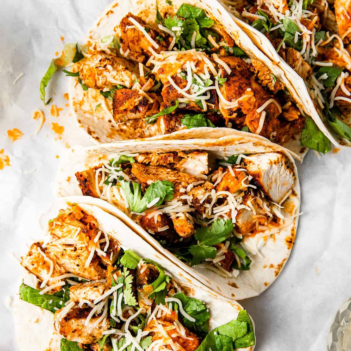 ancho chicken tacos with cheese, hot sauce, and lettuce.