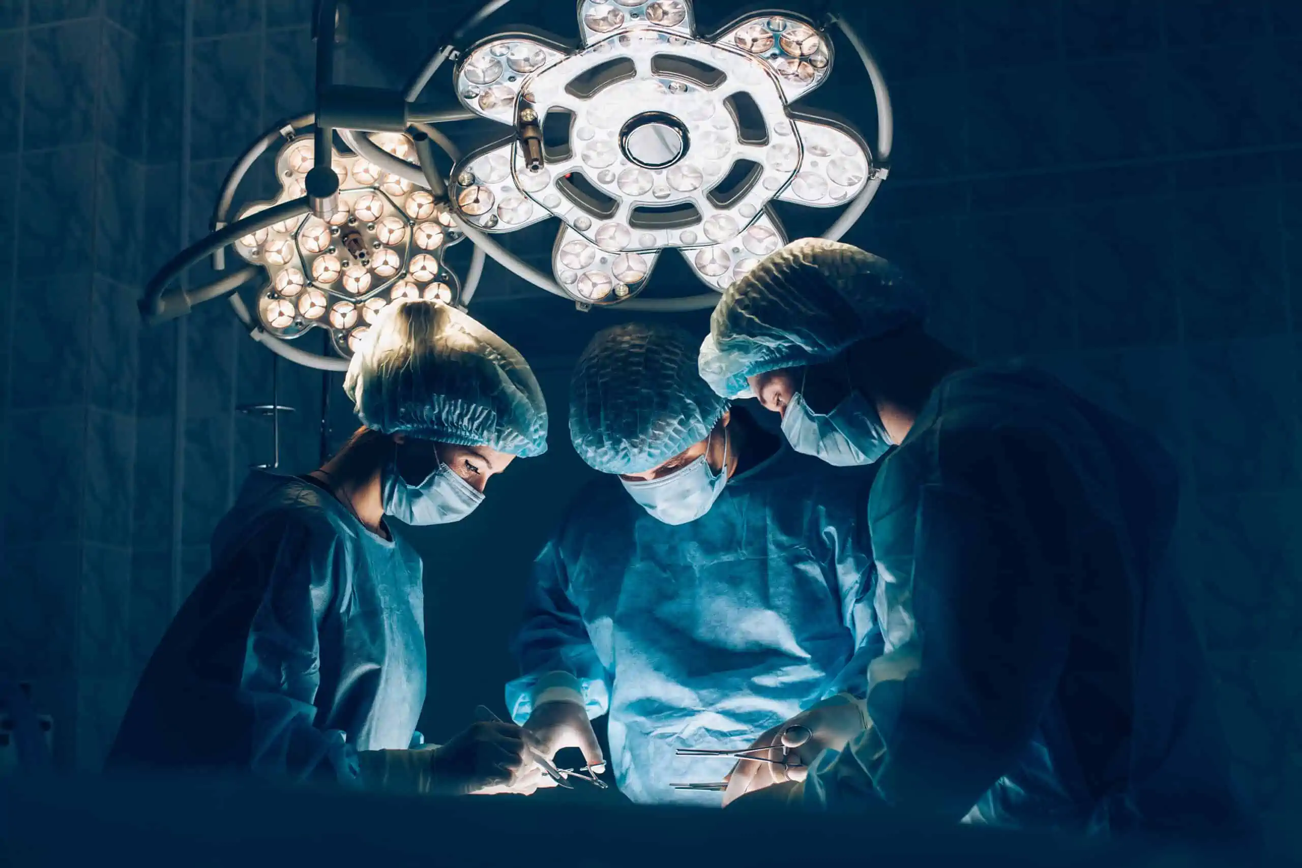 three surgeons performing a procedure in an operating room.