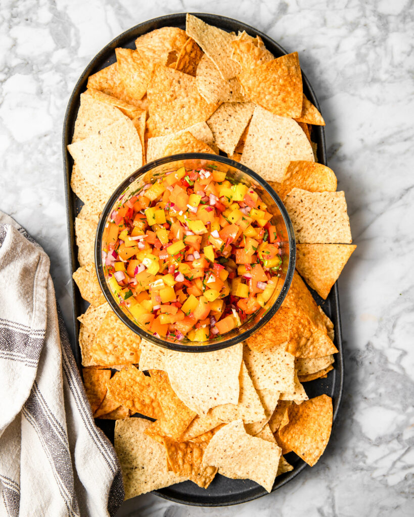 tortilla chips served with a bowl of bell pepper salsa.