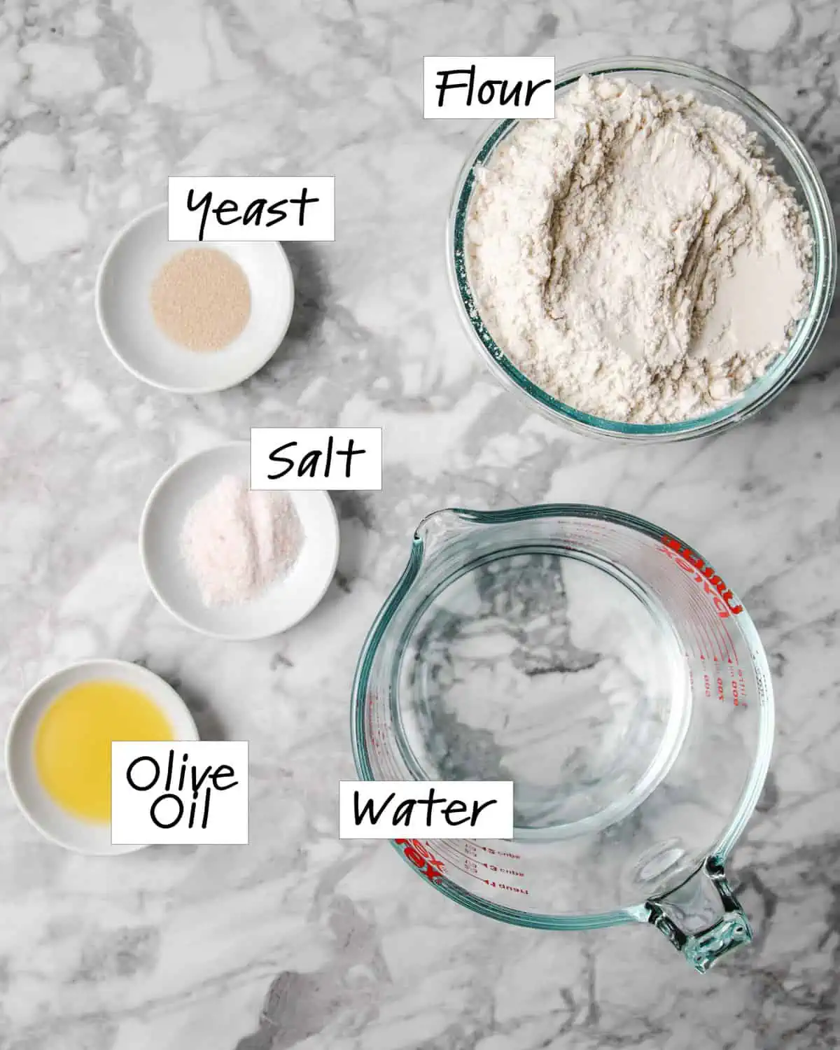 the ingredients, flour, yeast, water, salt on a marble counter.