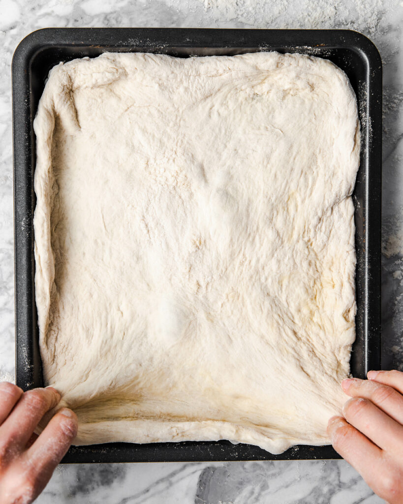 stretching dough out on baking sheet.