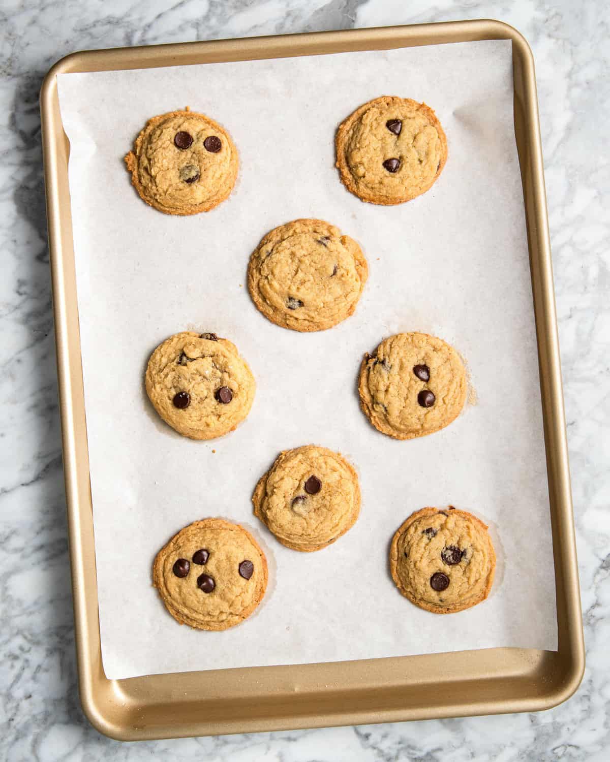 baked chocolate chip cookies on a baking sheet lined with parchment paper. 