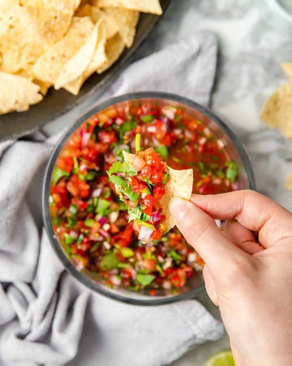 scooping fresh tomato salsa with a tortilla chip.