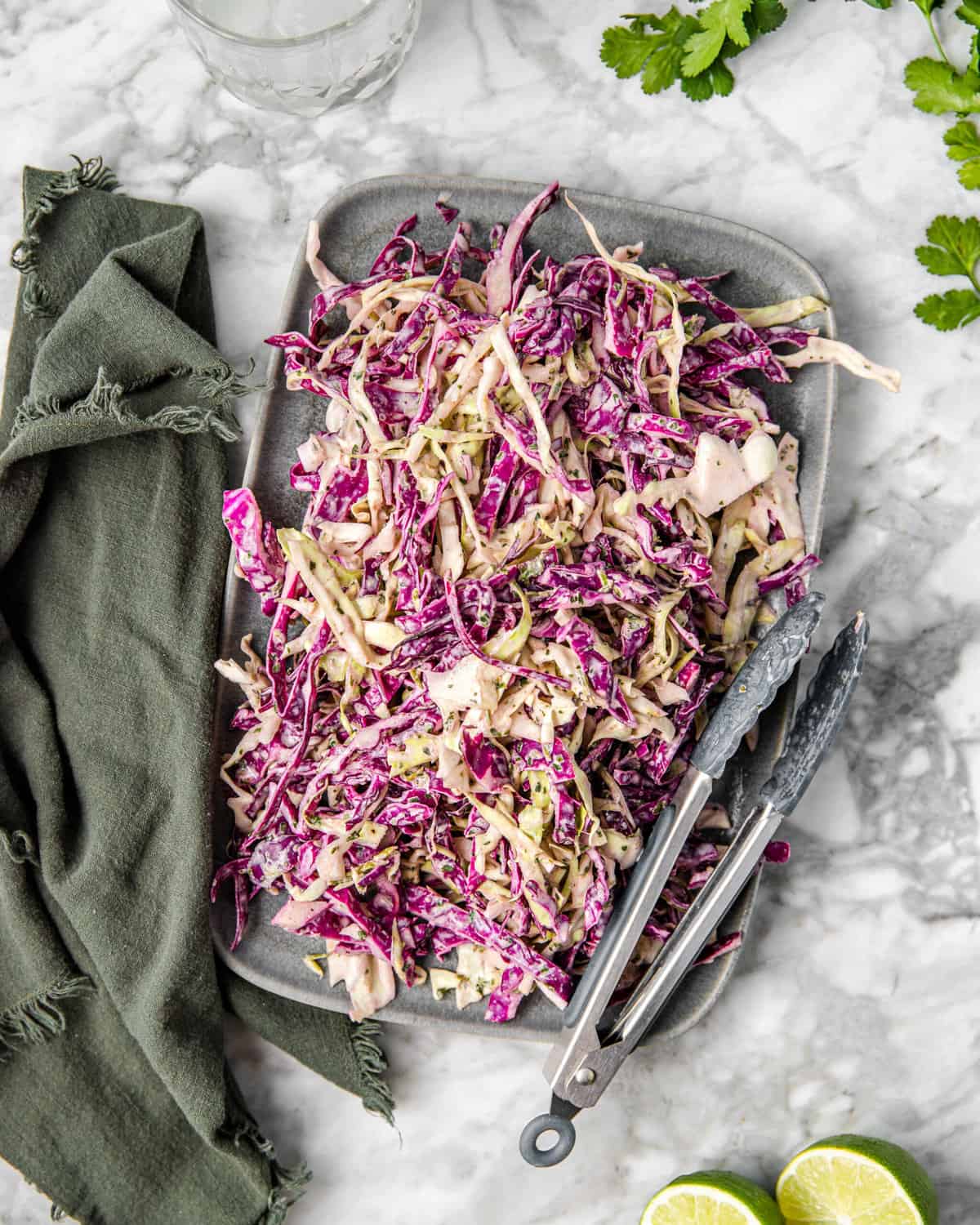 a plate of red and green cabbage salad with a cilantro lime dressing on a counter.