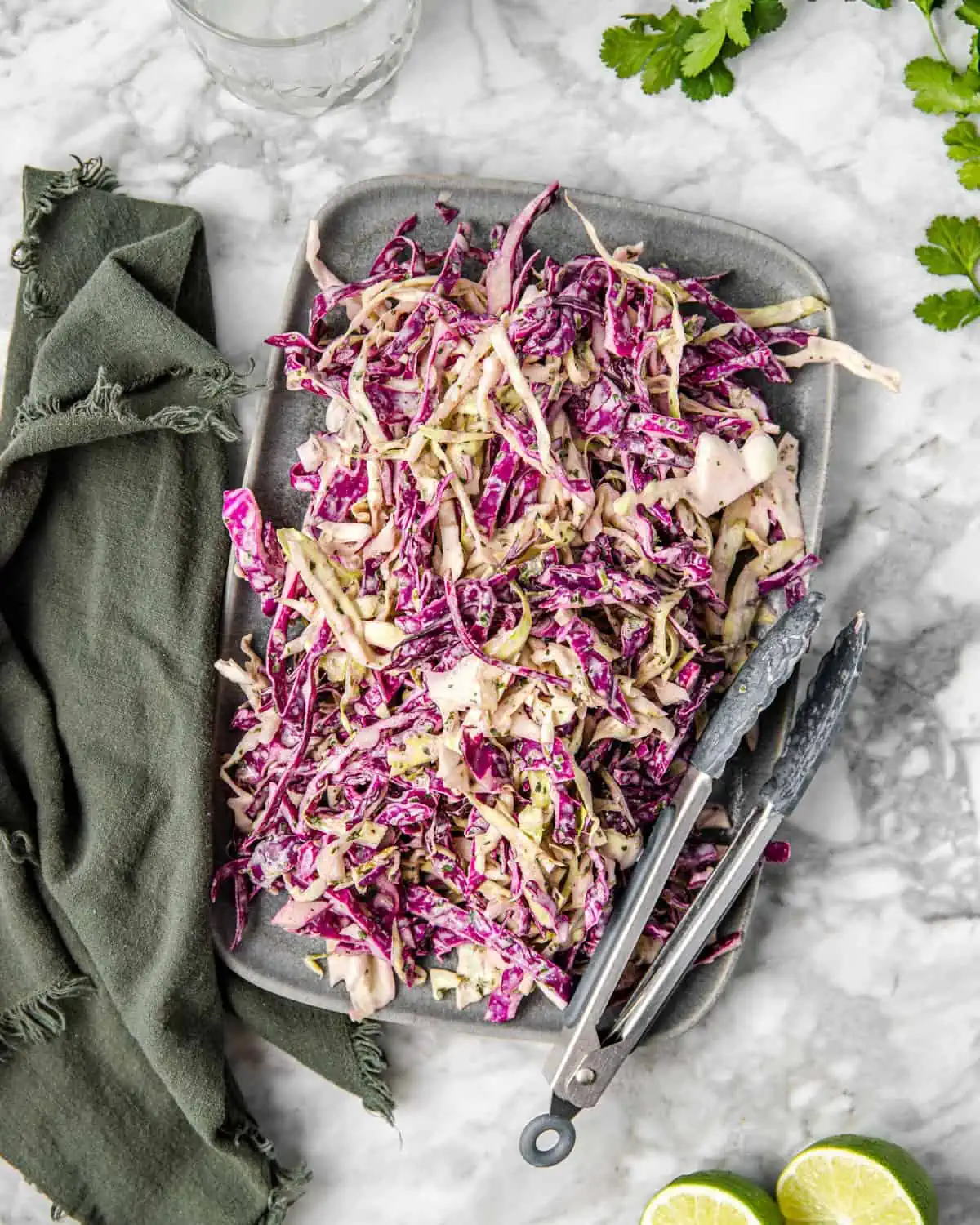 a plate of red and green cabbage salad with a cilantro lime dressing on a counter.