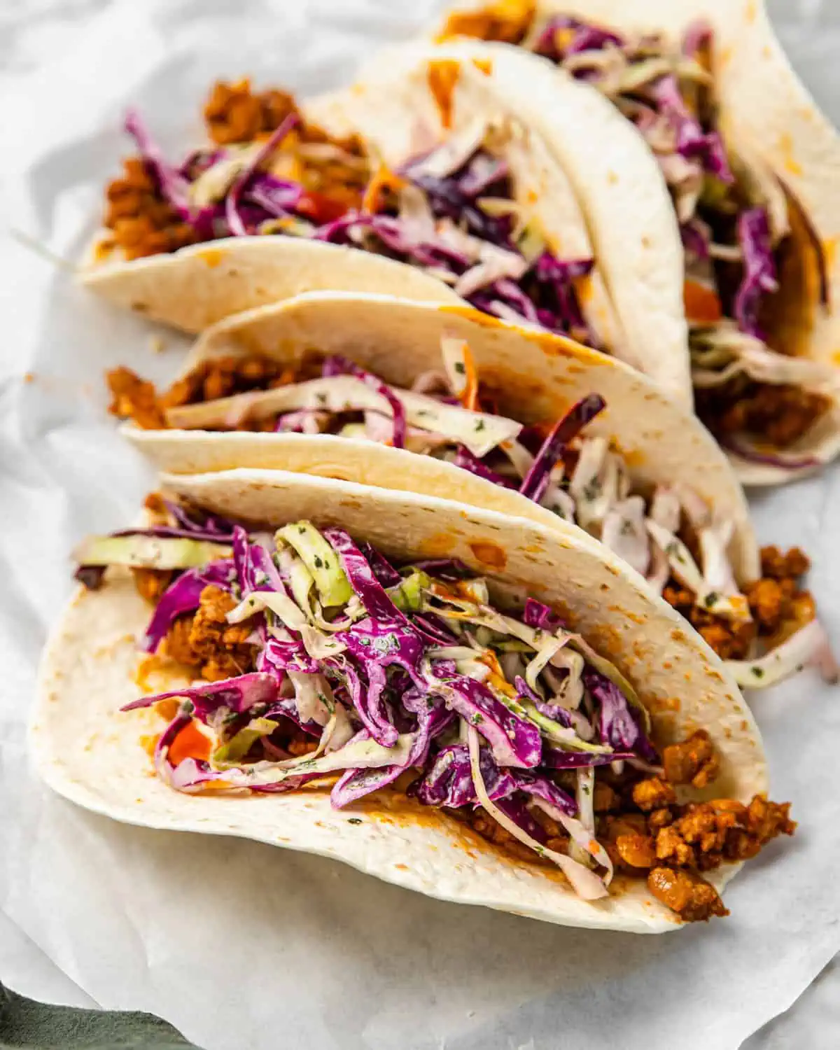 a taco with Mexican ground pork meat topped with cabbage slaw and hot sauce.